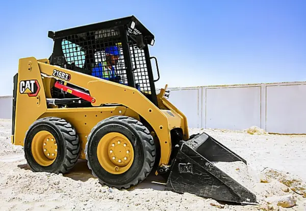 CAT skid-steer loader lifting dirt with its bucket at a construction site.